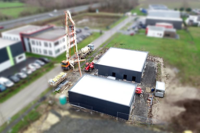 Dans cette prise de vue aérienne, on voit désormais les deux bâtiments, dont le bardage vient d'être installé. Place désormais aux installations intérieures, avec le coulage de la dalle.