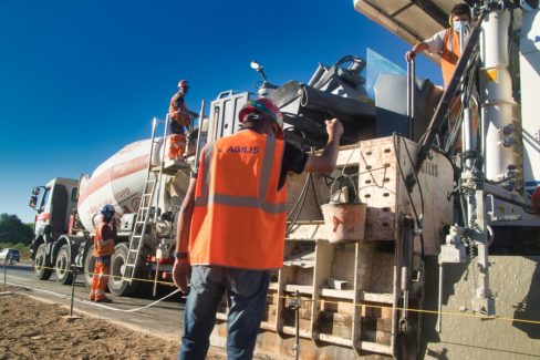 Une entreprise spécialisée coule du béton extrudé, sur l'axe Vannes-Nantes. Une bétonnière alimente en permanence le véhicule qui avance au rythme du parapet.