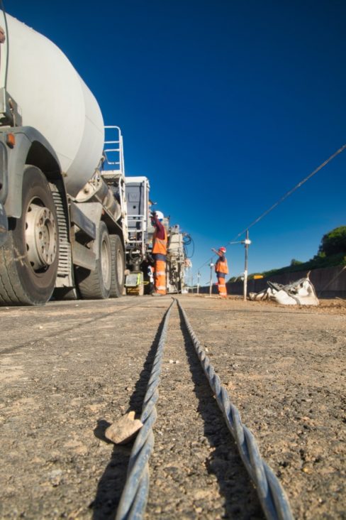 Un câble en acier est incorporé au béton fraichement coulé.