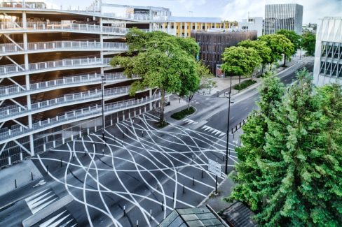 sur cette photographie aérienne prise à mi-hauteur , les passages piétons se jouent des lignes verticales du parking des machines situé à proximité. Un contraste en les lignes verticales et les zigs, les zags des passages piétons.