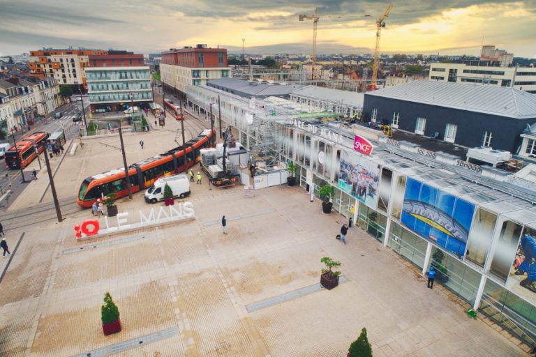 Suivi de chantier par drone à la gare du Mans. Prises de vues aériennes pour la filiale d'Engin, à savoir Axima, en charge de la réfection d'une partie des toitures. La photo a été prise depuis le parvis de la gare avec les services de sécurité. On y voit l'entrée de la gare ainsi que les fameux tramway oranges ainsi que les bus de la même couleur. A cette heure matinale le parvis de la gare est encore bien seul. Il faut dire que c'est l'a période des vacances, mais également d'une grève.