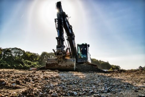 Photographie d'un tractopelle à contre-jour. La photo , un peu en contre-plongée nous montre la puissance de l'engin