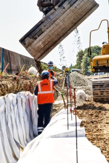 Suivi de chantier de la RN 165 à Nantes, au niveau de la bifurcation. Une tranchée, recouverte d'un géotextile est approvisionnée en graviers. Le godet déverse son contenu