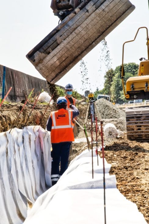 Suivi de chantier de la RN 165 à Nantes, au niveau de la bifurcation. Une tranchée, recouverte d'un géotextile est approvisionnée en graviers. Le godet déverse son contenu