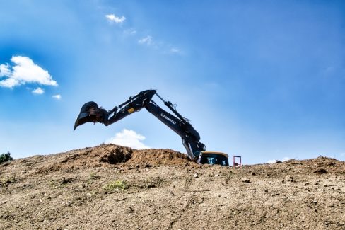 Un tractopelle surgit de la montagne, ses dents pointent vers le ciel avant de commencer à excaver.