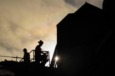 deux hommes travaillent sur une nacelle. C'est une photo en contre-jour. La photo a été prise pendant la première phase du suivi de chantier du château de l'Hermine à Vannes.