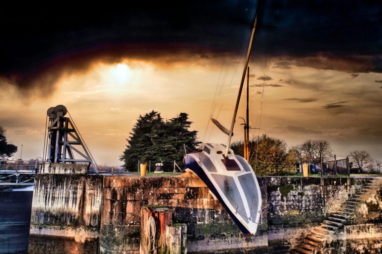 Malgré le temps, nous avons pu voler. Prises de vues par drones du fameux bateau mou sur le site de la Martinière au Pellerin. L’œuvre imaginé par Erwin Wurm s'intitule Misconceivable. Il s'agit d'un bateau posé hors de l'eau, et qui telle une guimauve épouse les formes du ponton sur lequel repose. Il semble vouloir se glisser dans l'eau. Sa coque bleu reflète l'eau de la Loire. Le ciel est très perturbé en arrière plan. Cet oeuvre fait partie du voyage à Nantes, le non moins fameux VAN