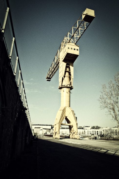 Une photographie aux couleurs vintage de la grue Titan jaune de Nantes. La rampe métallique située à ses côtés permet de donner une structure à la photographie