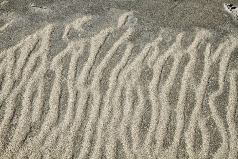 Sur un sable gris, témoin d'une basse mer, des lignes de sable plus fin et plus clairs se forment et parviennent à remonter la pente