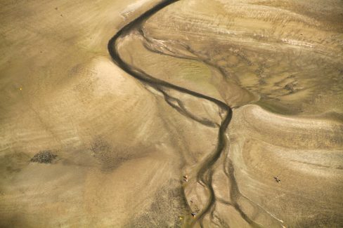 Des marcheurs se promènent en baie du Mont Saint Michel au milieu d'un décor surnaturel