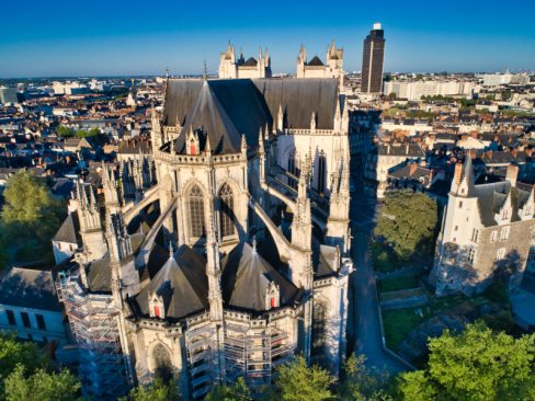 Vue aérienne de la face Est de la cathédrale Saint Pierre-et Saint Paul à Nantes réveille Nantes avec ses cloches matinales. Majestueuse, et rayonnante et bien que plus petite en terme de hauteur que la Tour de Bretagne (au fond), elle la domine de part sa majesté.