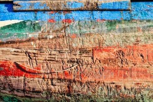 Une coque en bois d'un très vieux bateau de pêche en haute mer est abîmée. Elle a tellement vécue que les cordages ont laissé des marques sur le bastingage. Les couches de peinture successives se dévoilent et laisse deviner l'âge canonique de cette embarcation.