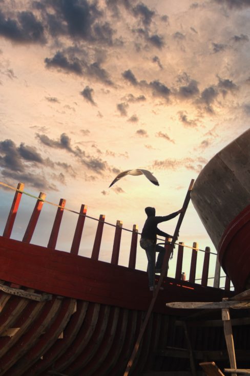 Un ouvrier sur un chantier naval à Essaouira au Maroc est en train de monter afin de travailler sur la construction d'un nouveau bateau de pêche hauturière.
