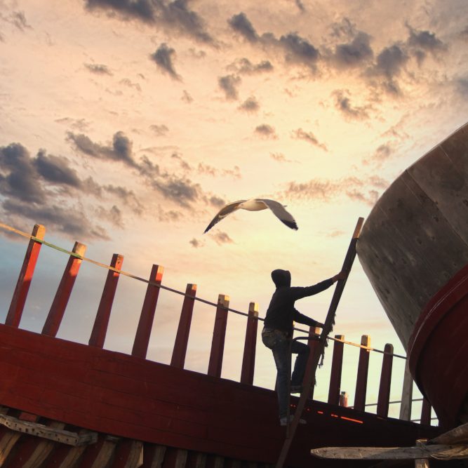 Un ouvrier sur un chantier naval à Essaouira au Maroc est en train de monter afin de travailler sur la construction d'un nouveau bateau de pêche hauturière.