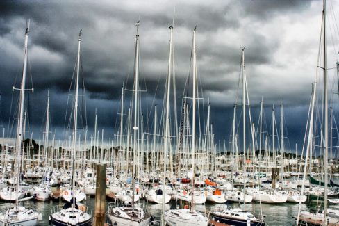 Le port de la Trinité sur Mer avant la tempête. Des myriades de mâts, de coques, de bateaux et de marins. Le ciel est très sombre, la tempête s'annonce/