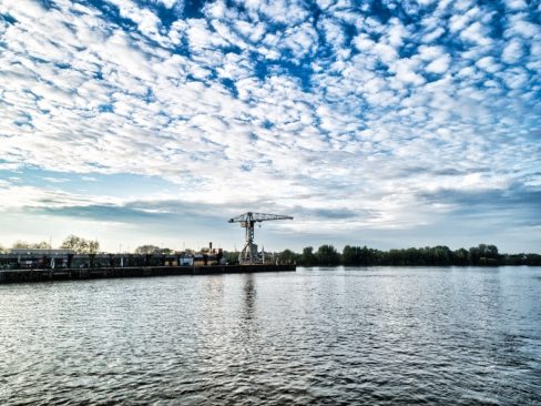 La grue Titan grise vue depuis la rive située en face, et proche de la carrière misery. Nantes se dessine et son parcours se complète. Une pluie de nuage blancs souligne la majesté de cette grue titanesque.