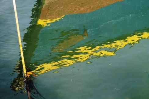 Une coque colorée de bateau se reflète dans les eaux paisibles d'un port du Morbihan. Les mondes marins se découvrent.