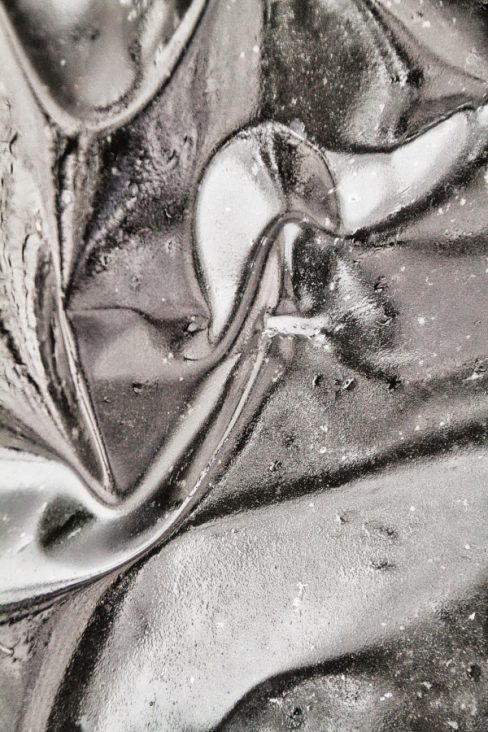 Une graine métallique est en train de germer. Sur un support métallique des teintes grises, blanches et noires donner des lignes, des formes, des directions.