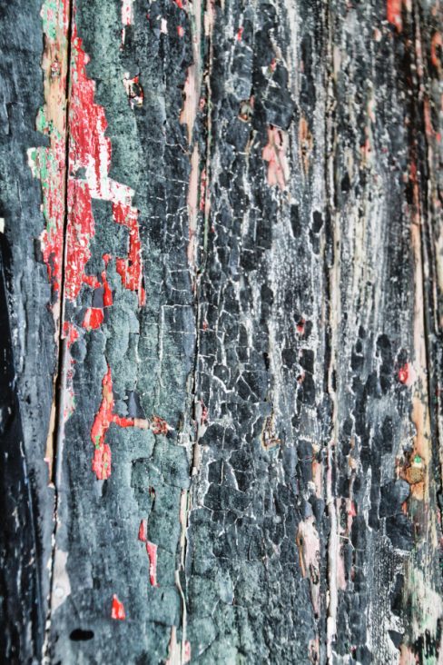 Une vieille coque de bateau en gros plan. La photographie , encore une aberration photographique me direz-vous, a été tournée est les lames de bois sont horizontales. On devine de multiples couches et sous-couches de peintures aujourd'hui écaillées. Bleu, vert, noir, rouge. Des paillettes de bois. Il faut sauver ces vestiges de l'histoire.