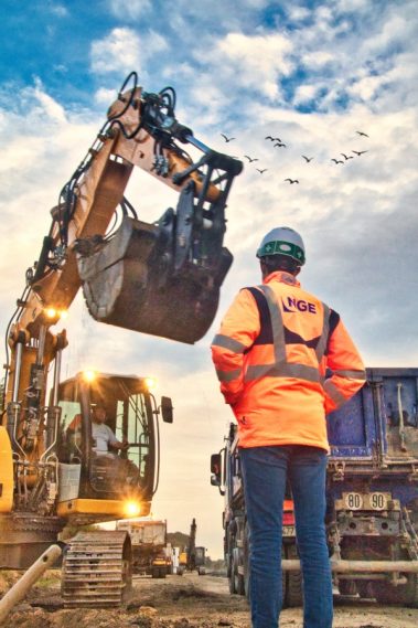 Suivi de chantier sur Nantes. Un conducteur de travaux de chez NGE contrôle les travaux d'excavation d'une pelle. Un camion-benne bleu est à côté de la pelle et reçoit de la terre