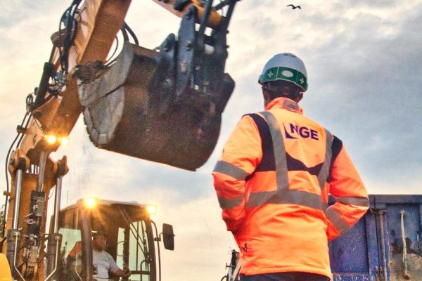 Suivi de chantier sur Nantes. Un conducteur de travaux de chez NGE contrôle les travaux d'excavation d'une pelle. Un camion-benne bleu est à côté de la pelle et reçoit de la terre