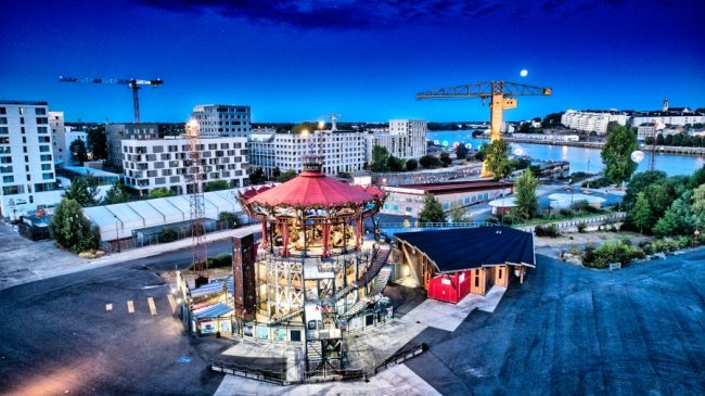 Le monde des deux Lunes. Le carrousel des Mondes marins imaginé par les célèbres Machines de l'île brille de mille feux à l'heure bleue. Les anneaux de Buren dans le fond tente d'attirer la pleine lune qui tutoie la grue jaune