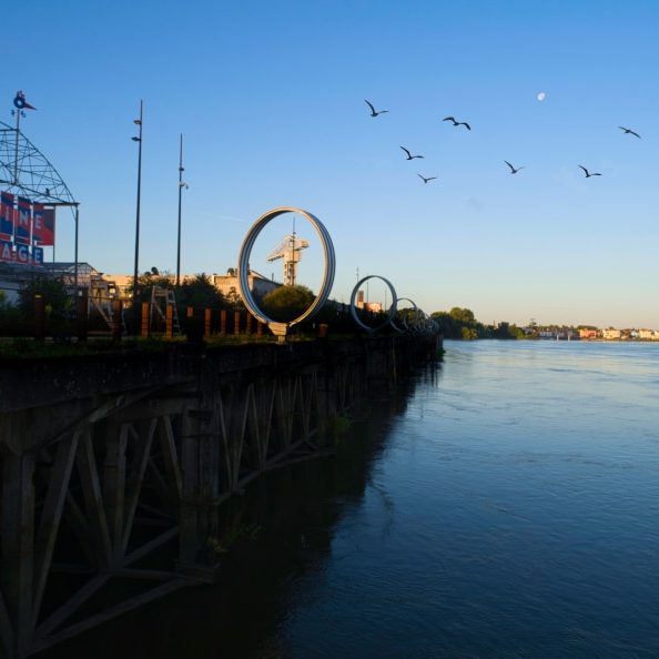 Une vue originale depuis le Loire de la Cantine du Voyage et les anneaux de Buren. Dans un de ces cercles, on aperçoit la grue Titan grise