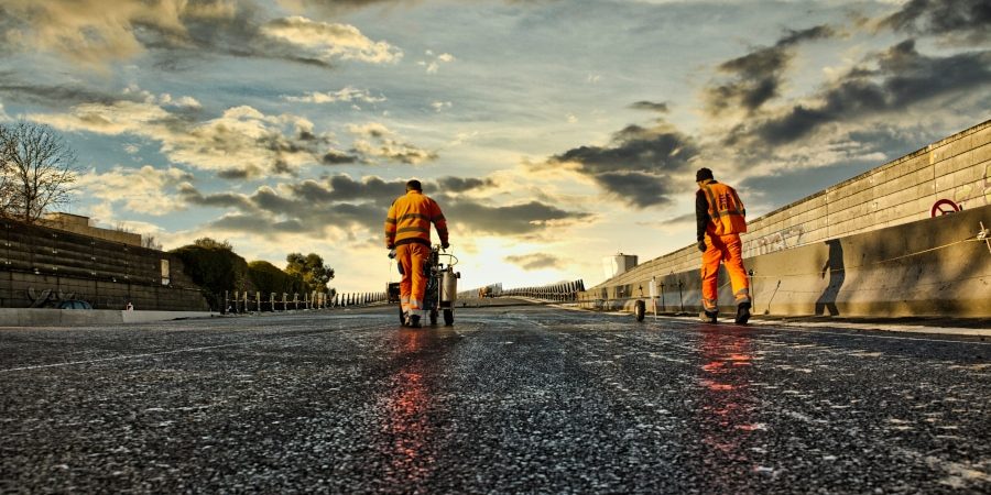 Ombre et orange Photo-reportage de chantiers. Deux hommes habillés de orange réalisent des travaux de marquage et pré-marquage au sol. Cette opération est nécessaire avant de procéder au marquage définitif de ce nouvel échangeur à la Roche sur Yon.
