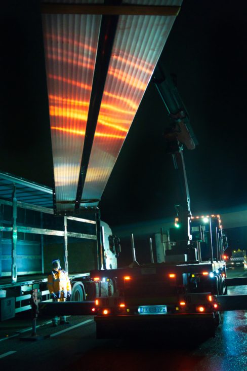 Prises de vues nocturnes du déchargement d'une potence sur une voie expresse.