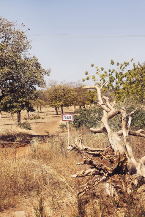 une pancarte signale une école. On se demande bien où ? Car, c'est la brousse et cette pancarte semble perdue au milieu de nul part.