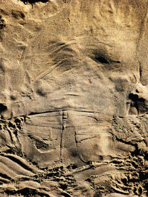 Une personne s'est allongée dans le sable. L'empreinte de son pantalon, un jean reste de manière éphémère gravé dans le sable