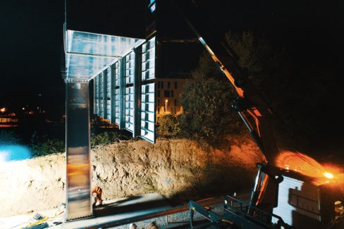 Vue de profil d'une potence directionnelle. Au sol, les hommes casqués sont en train de serrer les vis et les boulons.