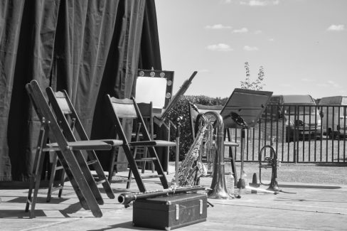 Une photographie en noir et blanc. Sur une scène installée à la campagne, des instruments à vents attendent leurs musiciens. Posés à l'envers, sortie contre terre, les notes blanches, les notes noires se sont tuent. Et comble du comble, même les silences sont réduits au silence.
