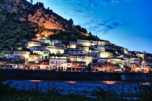 Destination Berrat en Albanie. Un magnifique village qui prend tout son sens et ses couleurs à la nuit tombée. Accrochées à un flanc de montagne les candélabres éclairent les façades blanches aux fenêtres de bois de cette ville quasi antique