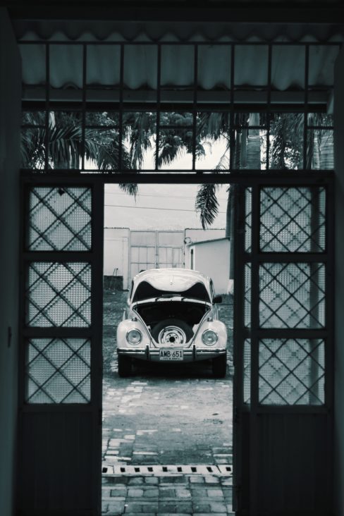 Une petite coccinelle de chez VW attend son pilote le capot ouvert. Photo en noir et blanc donnant un côté rétro à cette photo