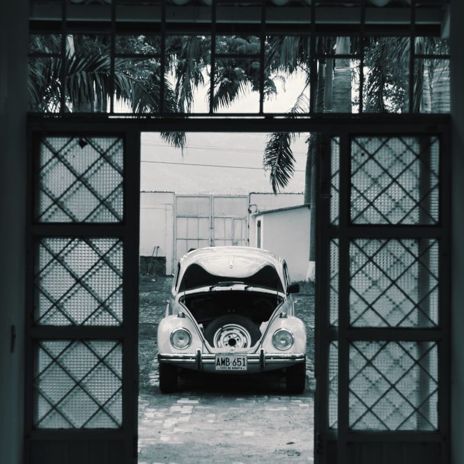 Une petite coccinelle de chez VW attend son pilote le capot ouvert. Photo en noir et blanc donnant un côté rétro à cette photo