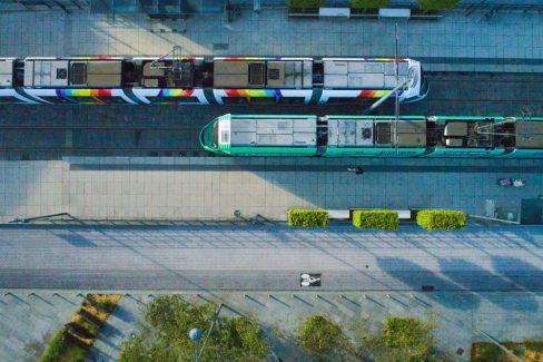 Vue aérienne de deux tramways très colorés de la ville d'Angers. Vue zénithale au niveau d'un arrêt de tram, comme on a coutume de dire. On peut clairement distinguer cet axe multi-modale entre les transports publics, et le partage de la route entre cyclistes et voitures. Nous sommes ici en zone 30, et pour cette raison, il n'y a pas de passage piéton.