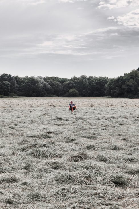 Une photo raconte une belle histoire. Un homme est assis sur une chaise de camping au milieu d'un champ. Il porte des écouteurs. écoute-t-il de la musique ? Non, il est en réunion. Ce champ est vaste, et l'herbe est fraîchement coupée. Bien qu'il soit en réunion, il semble que cet homme est seul au milieu d'un festival, et attend que celui-ci démarre.