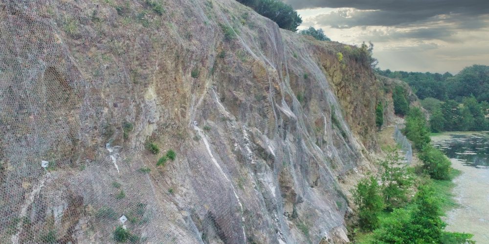 Réception d'ouvrage et compte rendu. Des nouveaux filets de protection ont été installés sur la falaise de la carrière de Saint Herblain en Loire-Atlantique afin d'éviter la chute de pierres, et contenir les éboulements. En bas, près de la berge, une clôture stop-chute a également été implantée.
