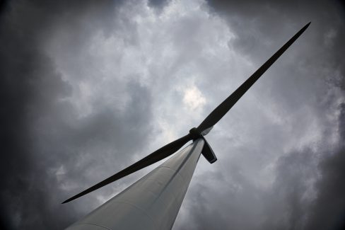 Au pied d'une éolienne. Le ciel est sombre et chargé. Il faut maintenant arrêter les moteurs et les pales de ce moulin à vent. Car , en effet, nous devons en faire l'ascension.