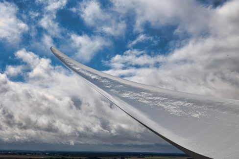 Non, ce n'est pas une aile d'avio, mais bien une pale d'éolienne en fibre de verre et de carbone. Elle transperce les nuages où une éclaircie a bien voulue se montrer.