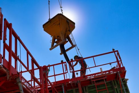 Un ouvrier casqué est en train de réceptionner du béton à couler. Ce béton se veut être décarboné.
