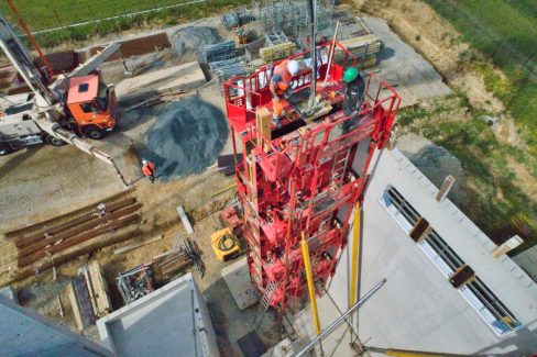Coulage d'un béton dit décarboné sur un bâtiment en construction. Le camion pompe alimente cette gigantesque tour de métal destinée au coffrage.