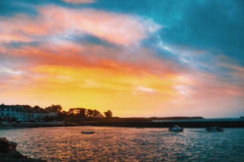 Le soleil se couche sur le port de Portivy. La mer se pare des couleurs jaune, rouge, et rose du ciel
