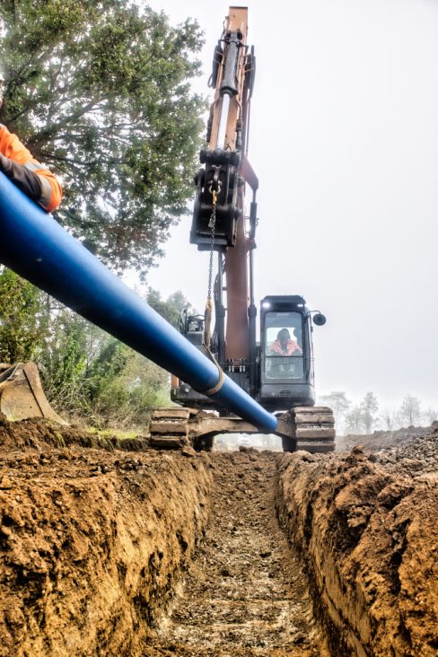 Une fois la tranchée creusée, la pelleteuse amène un tuyau qui sera par la suite enfouit.