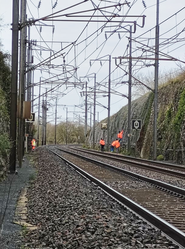 SDCH-Voies Ferrées-INGRANDES Des hommes vêtus de orange vérifient et inspectent les derniers travaux de renforcement d'une paroi en bordure de voie ferrée. Des prises de vues techniques par drone seront effectuées pour l'établissement du DOE
