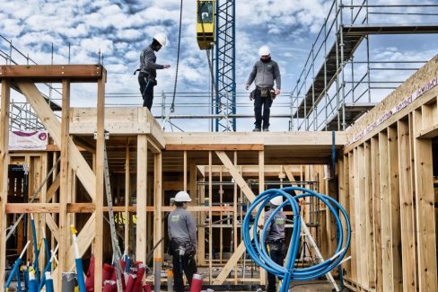 Une équipe de charpentiers de l'Atelier Isac s'organise lors d'un levage XXL. Un binôme est à l'étage, et l'autre en bas afin de réceptionner des panneaux de toitures