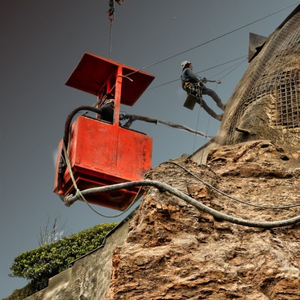 Travaux de cordistes Deux hommes d'une entreprise de cordistes sont en train de mètre en place du béton projeté.