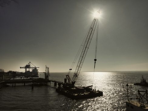 Suivi de chantier en cours sur le port autonome de Nantes-St Nazaire. Au premier plan, une barge s'apprêtèrent à lever un marteau pour enfoncer un pieu préalablement fixé par une autre barge.