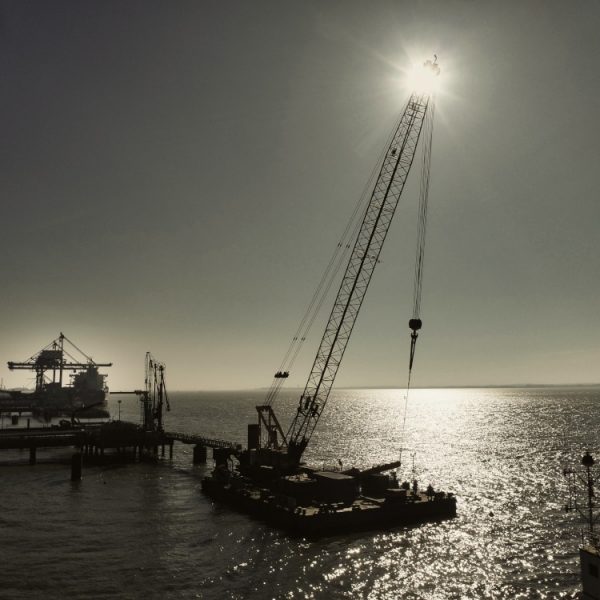 suivi de chantier sur l’estuaire Suivi de chantier en cours sur le port autonome de Nantes-St Nazaire. Au premier plan, une barge s'apprêtèrent à lever un marteau pour enfoncer un pieu préalablement fixé par une autre barge.